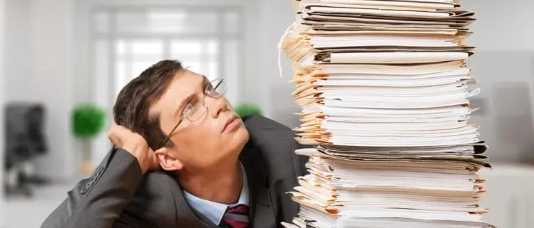 A man looking at a pile of documents, while thinking of the advantages of a C Corp and LLC
