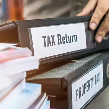 Tax return and property tax folders stacked with black binder