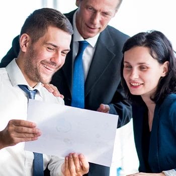 Three business persons looking at a single file and smiling
