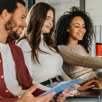 Team members smiling while using laptop