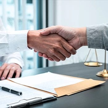 Shaking hands to someone as a sign of agreement above documents