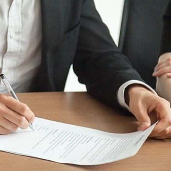 A person writing signature to a business insurance form