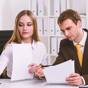 Two office people handling paperwork for an LLC operating agreement